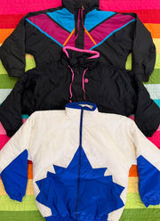 Two colorful vintage ski jackets, one black with neon trim and one white with blue and orange panels.