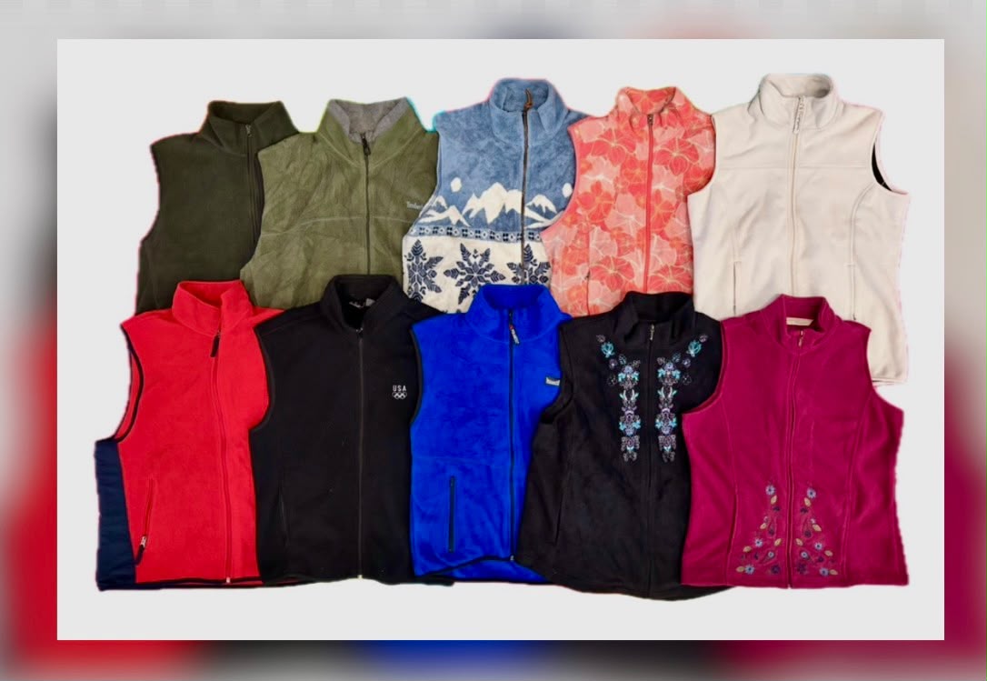 Assorted sleeveless fleece gilets in red, black, blue, olive, cream, and patterned fabrics, arranged in two rows.