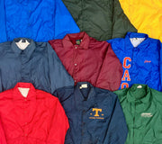 Assorted vintage coach jackets in blue, red, green, and burgundy, with snap fronts and embroidered logos.