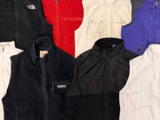 Assorted fleece gilets in black, red, cream, and purple, with high collars and zip fronts.