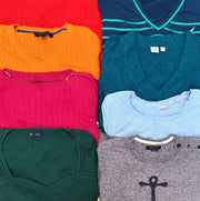 A colorful assortment of ladies’ knit sweaters in orange, pink, green, teal, light blue, and gray, with varied necklines and