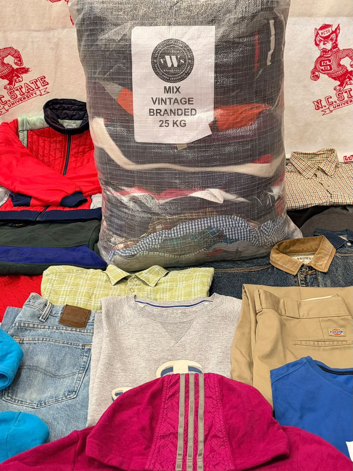 Clear 25 kg sack of mixed vintage branded clothes, packed with colorful shirts and jackets.