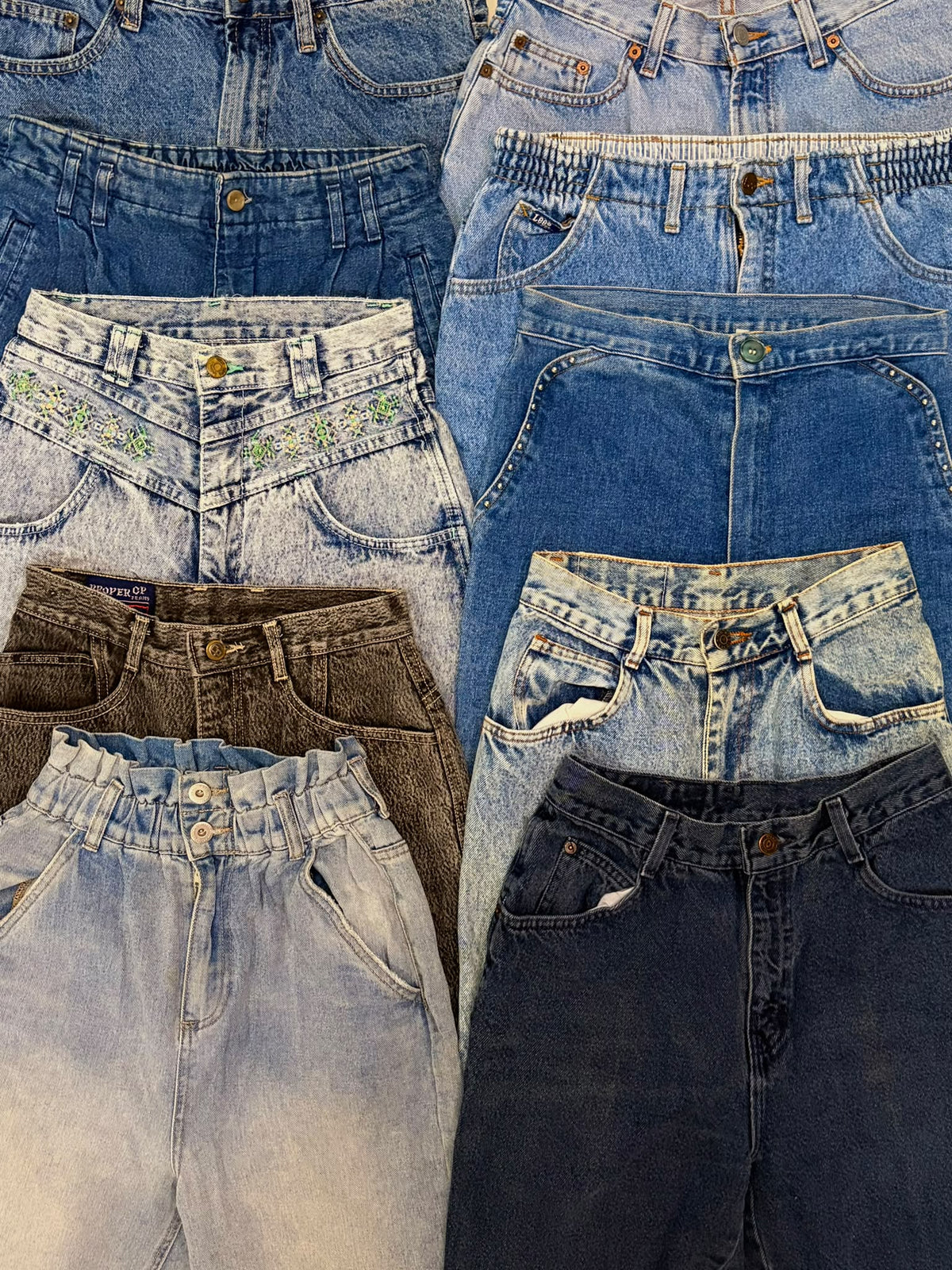 Assorted high-waisted mom jeans in blue, faded light wash, and dark denim with varied pockets and stitching.