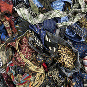 Assorted silk ties in various patterns and colors including stripes, plaid, animal print, and geometric designs stacked.