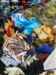 Pile of assorted colorful scarves in various patterns and fabrics, including floral, abstract, and geometric designs.