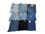 Stack of ten assorted Levi's jeans in various washes of blue and black denim with visible leather brand patches on waistbands.